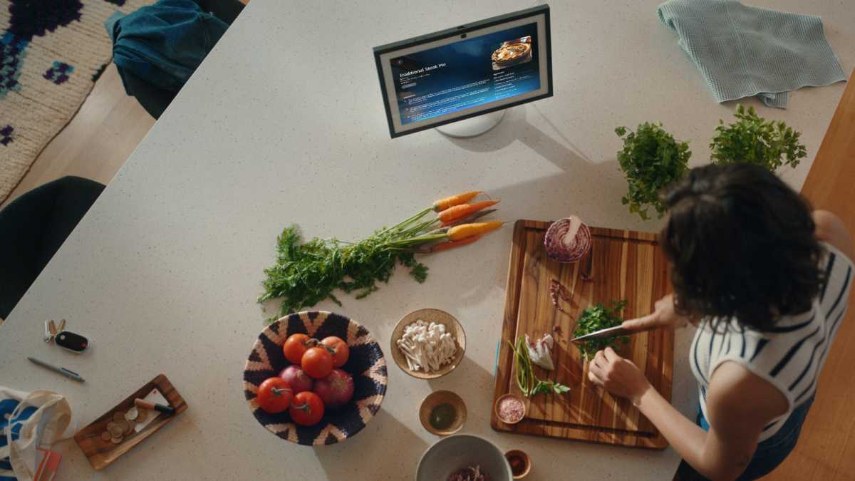 A woman preparing vegetables with an Alexa+ device nearby